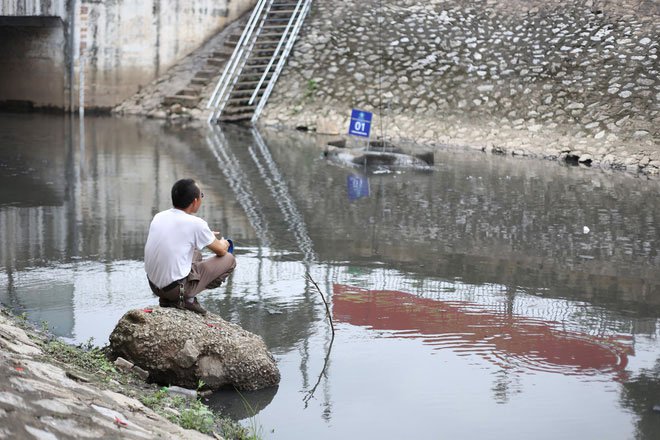 Người dân thong thả ngồi câu cá bên bờ sông Tô Lịch